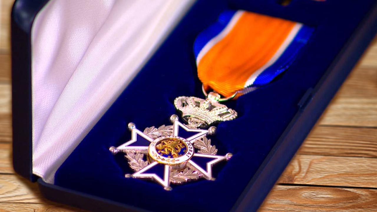 Hans van de Linde ontvangt de versierselen van de Orde van Oranje Nassau uit handen van de burgemeester van Schiedam
